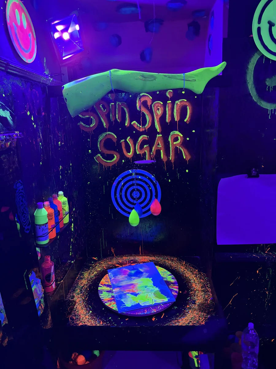 Corporate team in glowing white ponchos having a neon paint pistol fight under UV lights